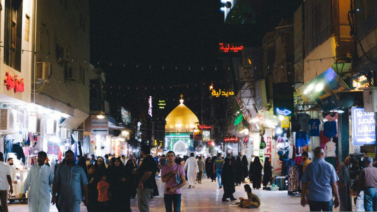 A crowd of people walking down a street at night.
